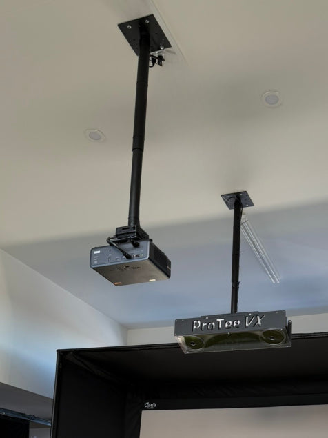 A projector and a golf launch monitor secured to the ceiling with adjustable black poles and a General Purpose 8x8″ Adapter Plate.